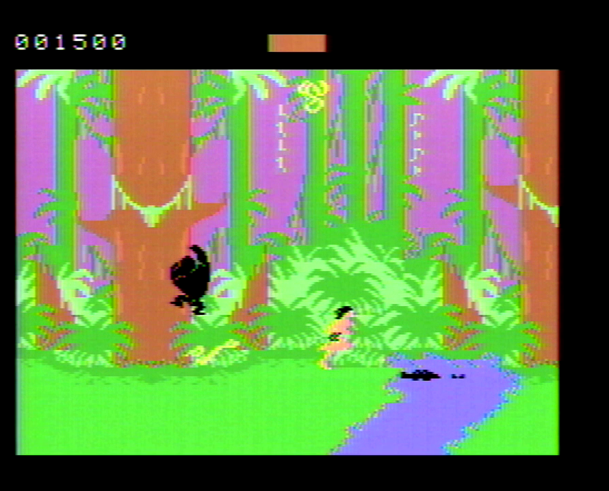 Tarzan moves through the jungle on the ColecoVision version. There is a gorilla on a tree behind him and a crocodile in the stream in front of him.