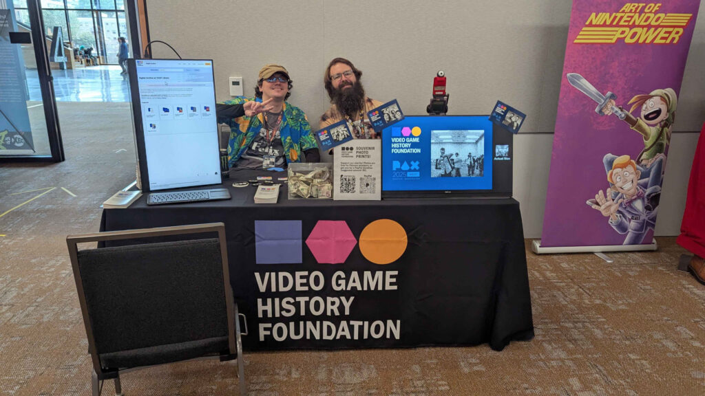 Two people sitting at a table with the Video Game History Foundation logo on a tablecloth.