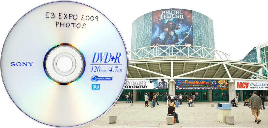 A DVD+R labeled "E3 Expo 2009 photos," overlaid on top of a photo of the LA Convention center during E3 2009.